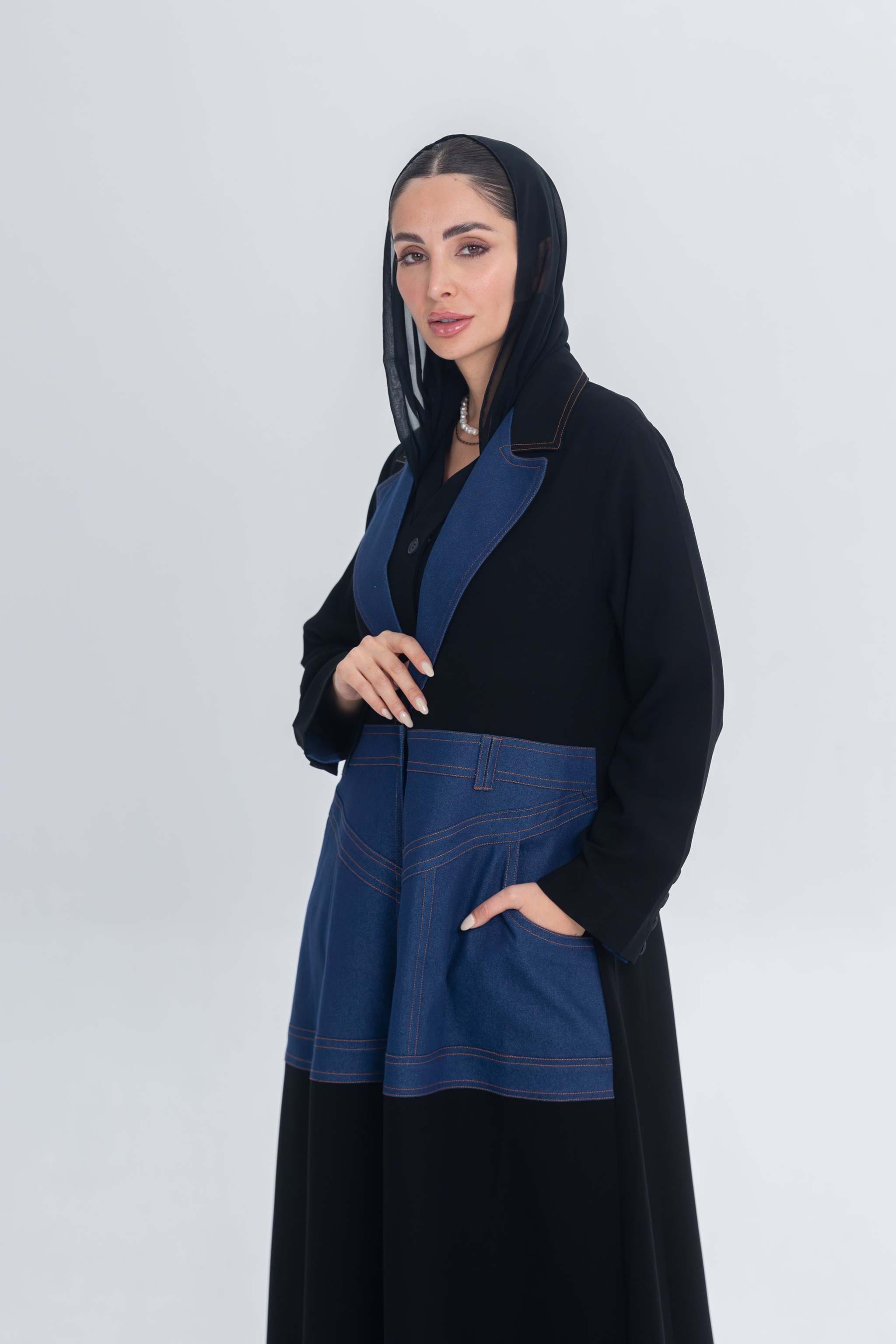 Woman wearing a black crepe abaya with blue denim panels and hood, featuring a modern and elegant design.