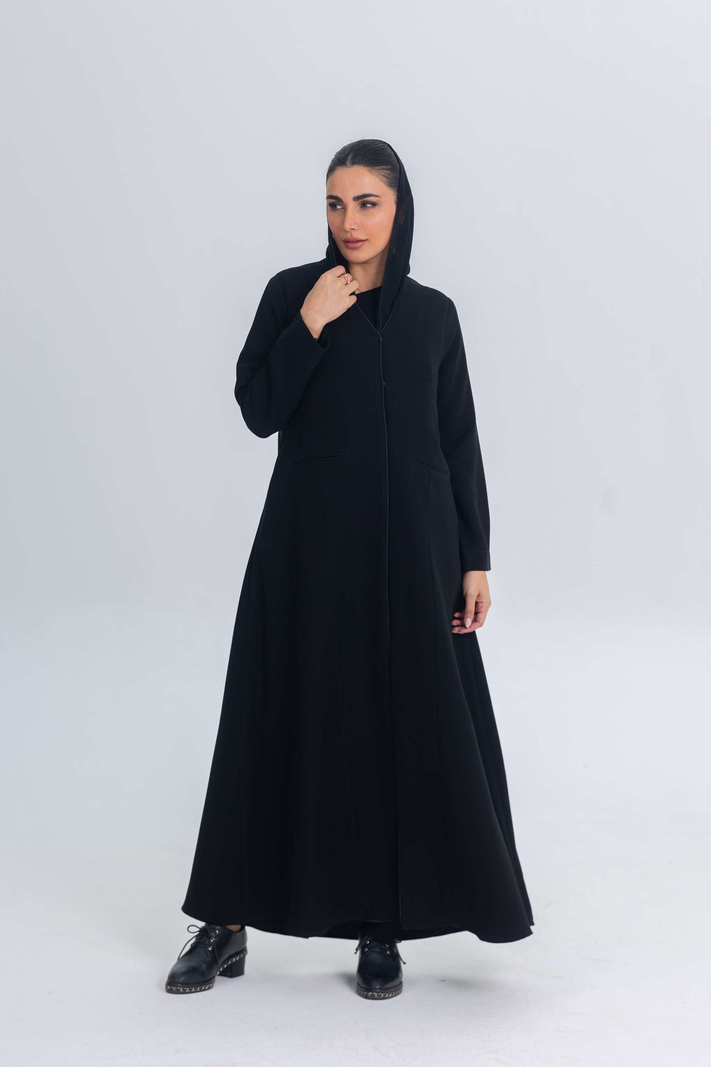 Black crepe abaya with subtle satin details, worn by a woman in a modest, elegant style.