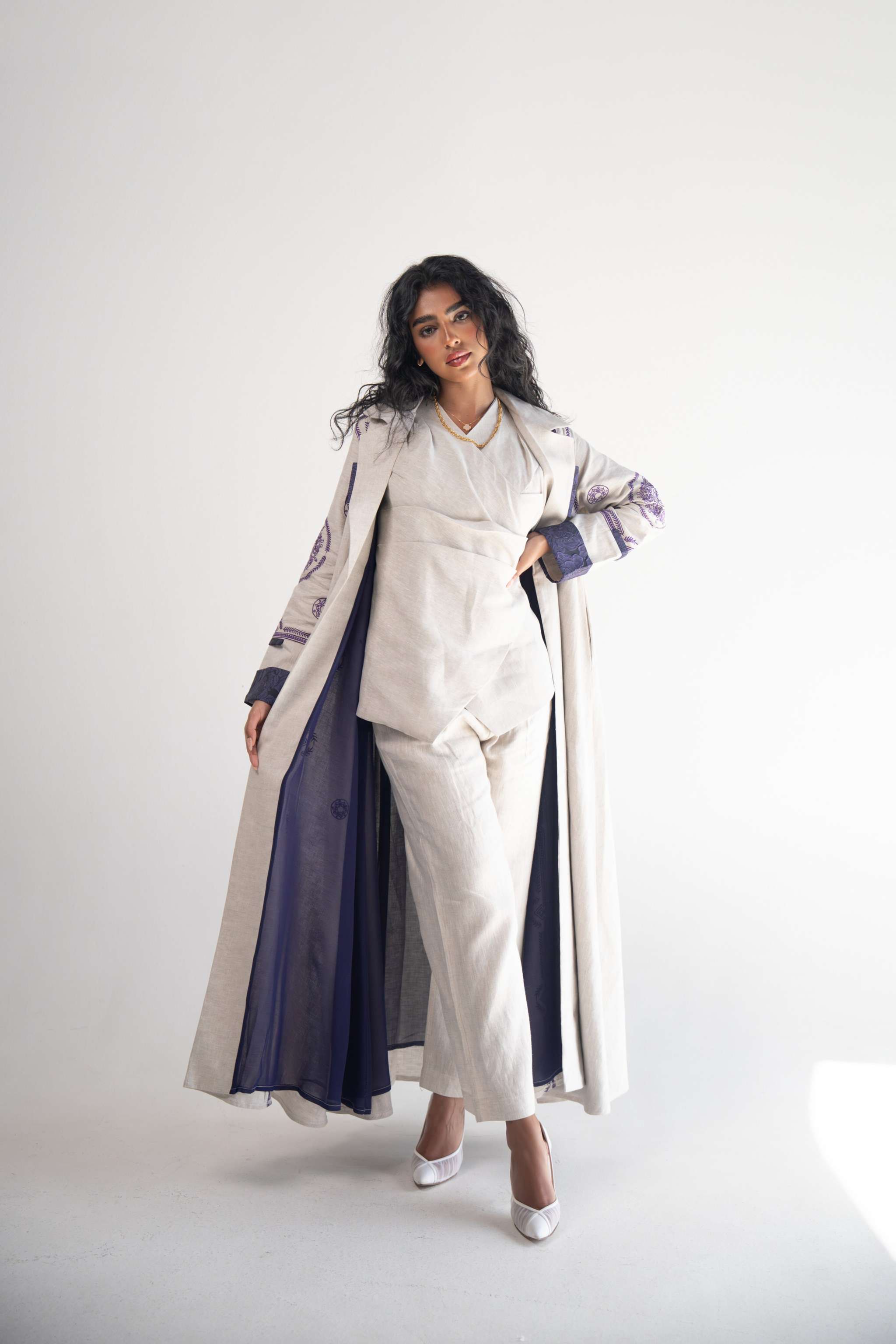 Beige linen blazer abaya with purple geometric and circular embroidery on sleeves, sides, and back, featuring a classic collar and purple chiffon inner lining.