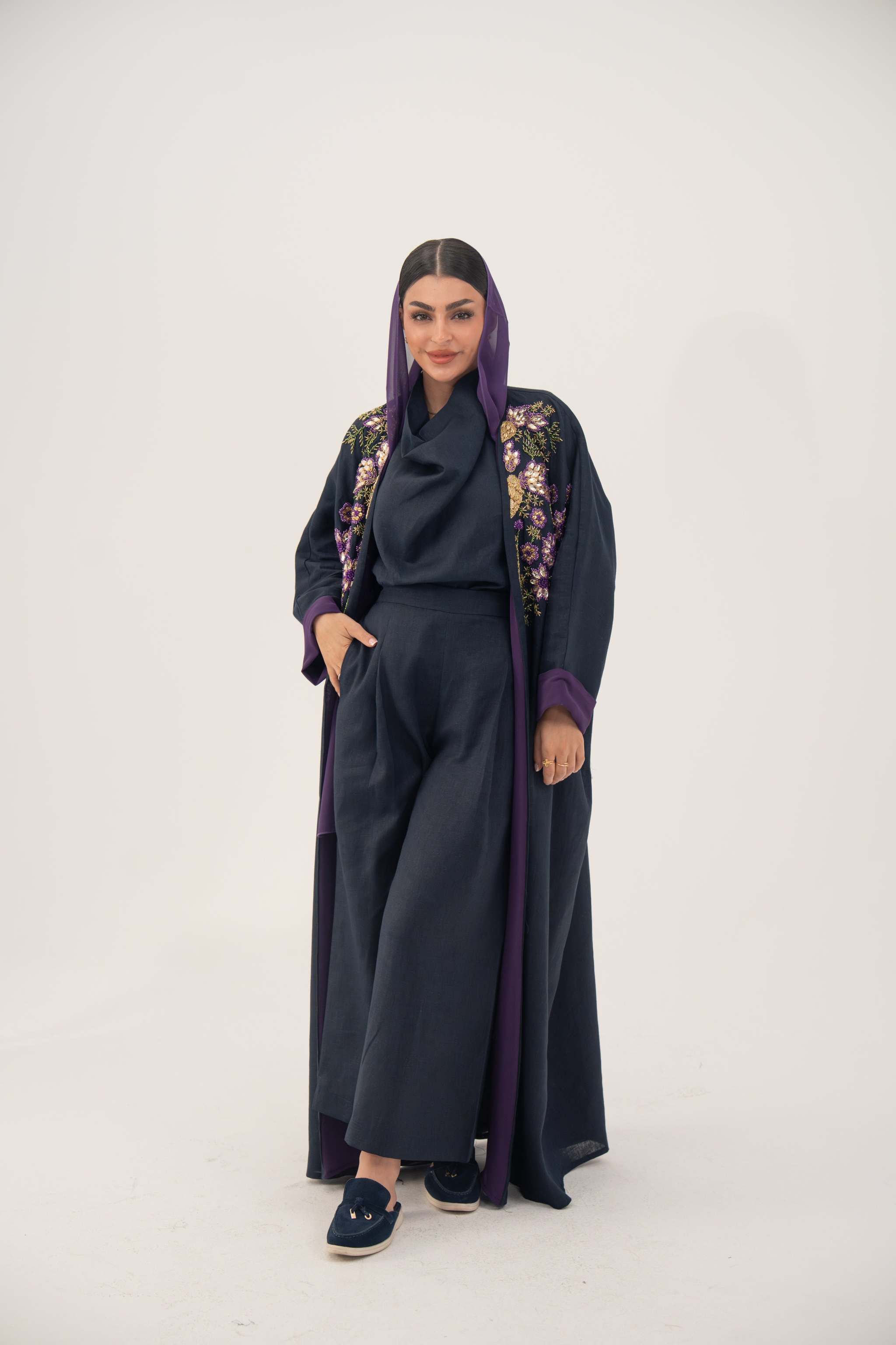 woman wearing navy blue linen-blend abaya with hand-stitched floral details and purple cuffs