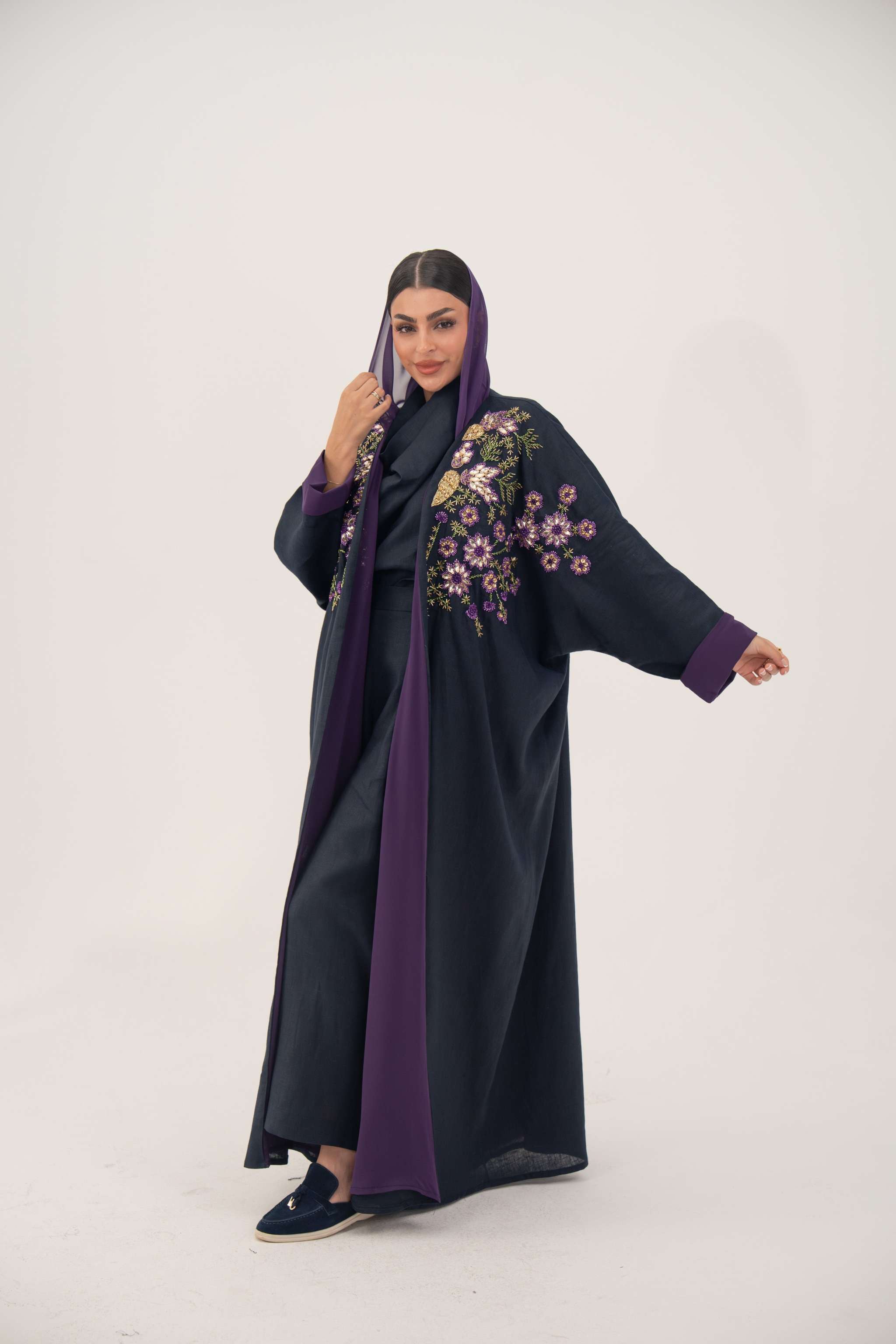 Navy blue linen-blend abaya with purple, gold, and green hand-stitched floral details and wide bisht style with purple cuffs and chiffon lining.