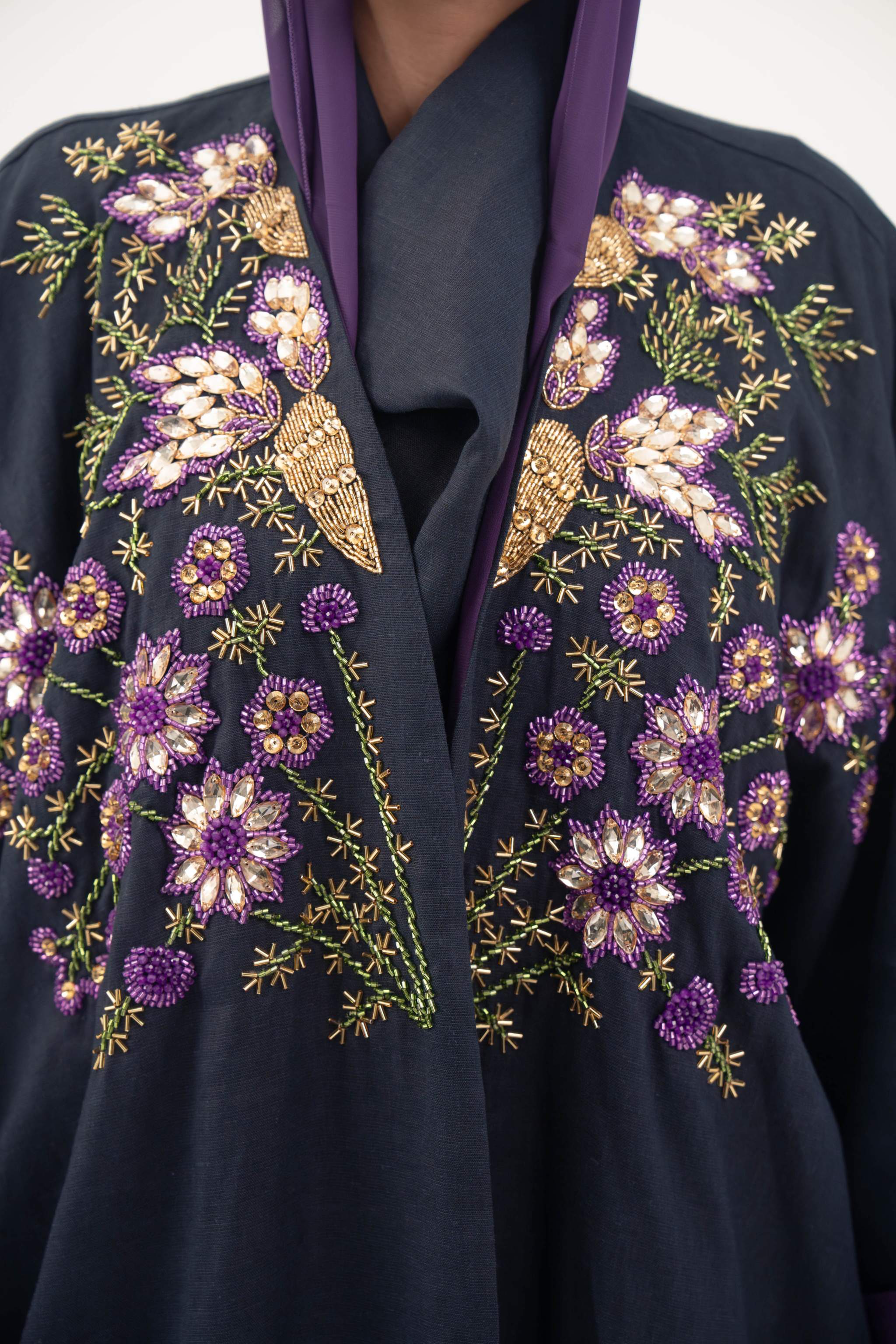 close-up of navy blue linen-blend abaya with intricate purple, gold, and green hand-stitched floral embroidery