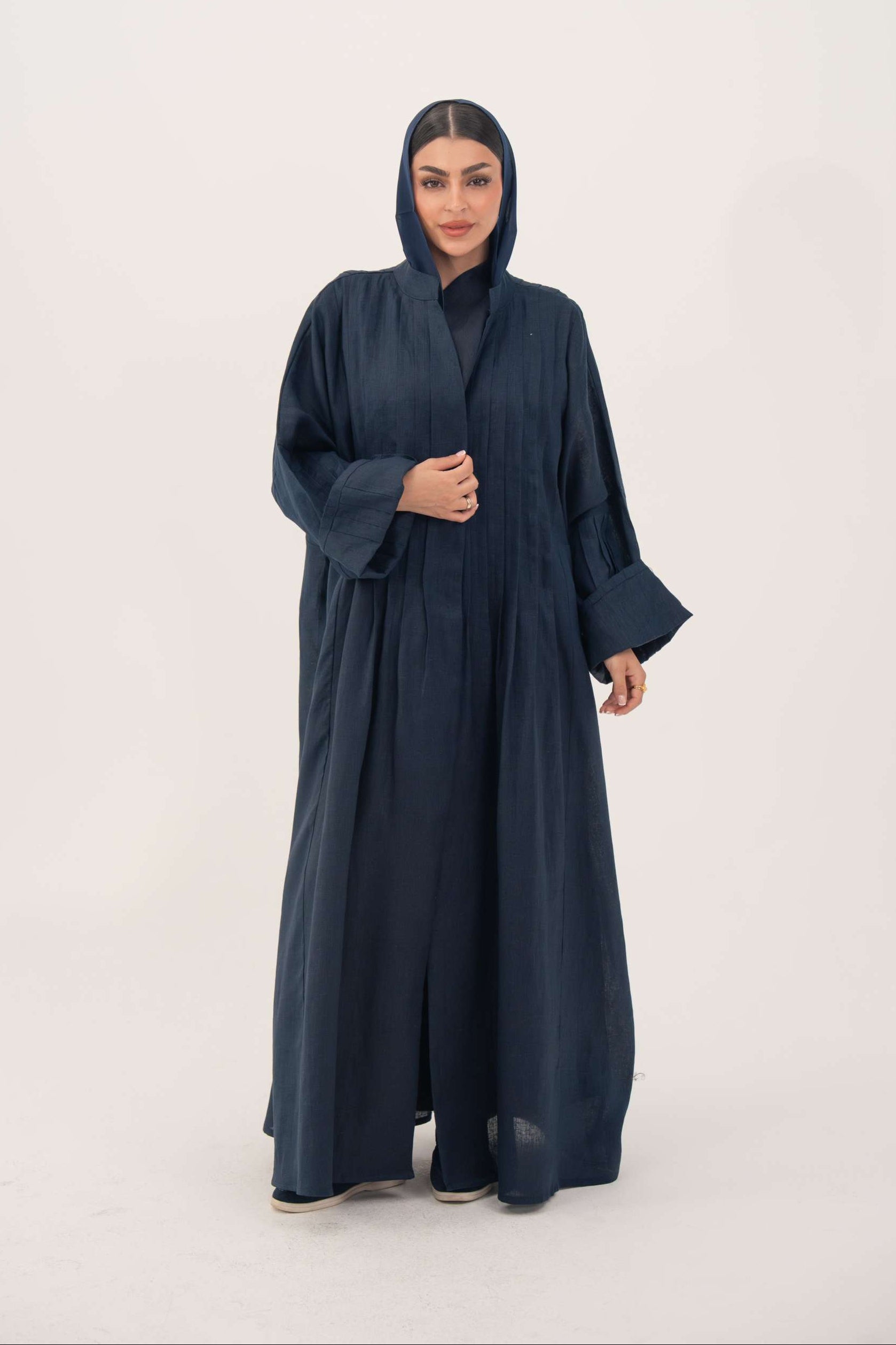 Woman wearing deep navy blue full-length open-front abaya made from lightweight linen with vertical stitched pleats and a minimalist design