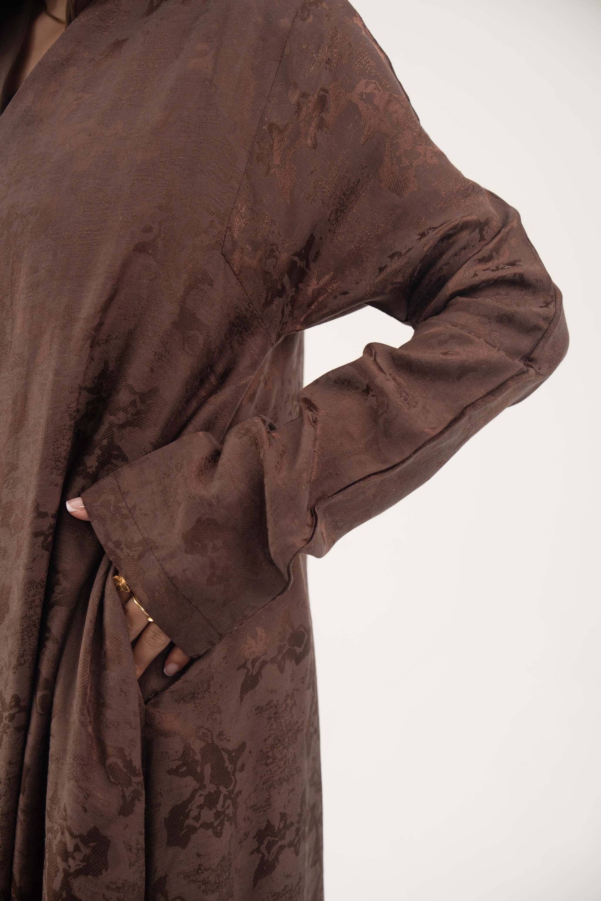 Jacquard silk Mercury abaya in warm cocoa brown with subtle floral pattern and long sleeves.