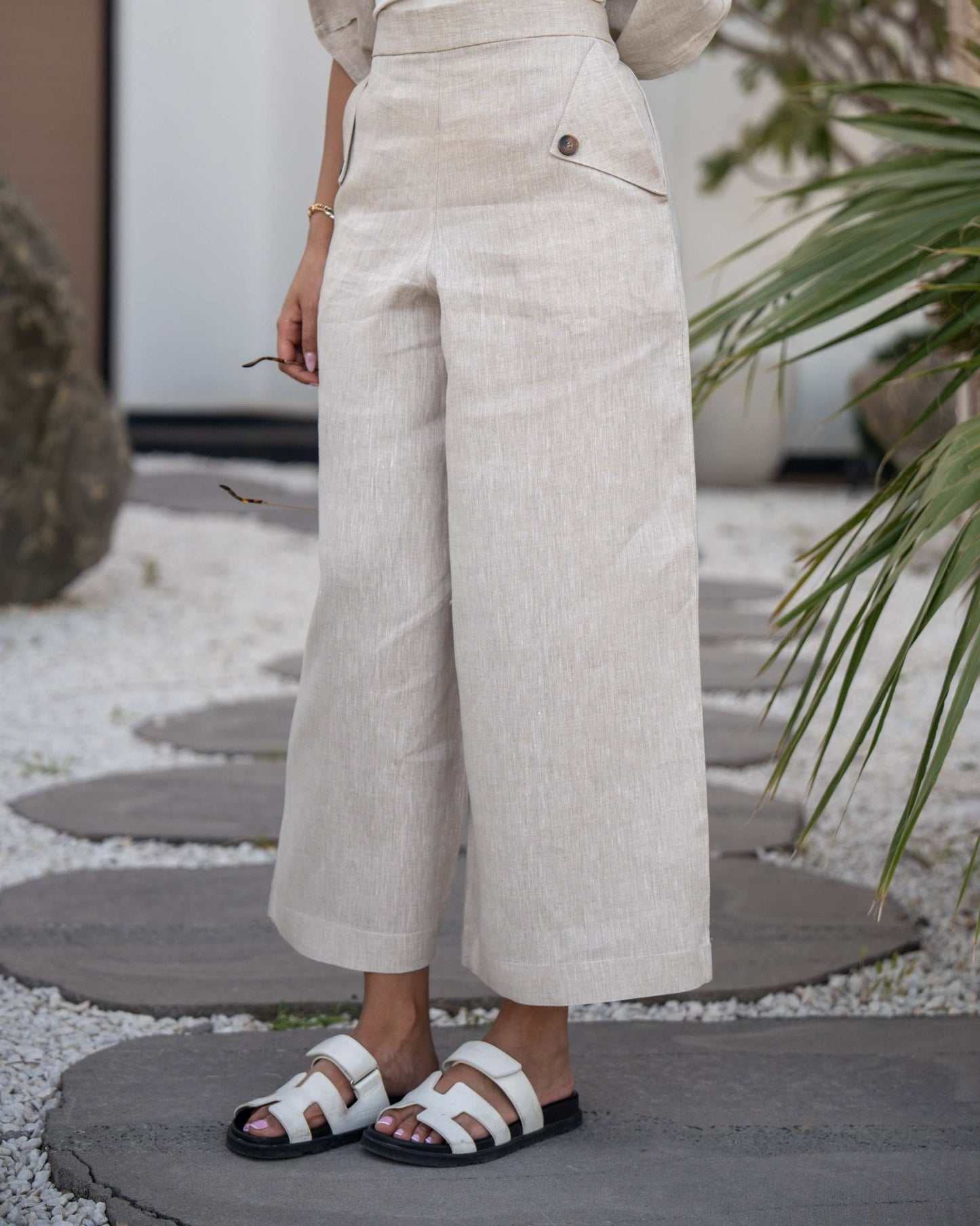 Beige Modern Pant with high waist and button details, cropped length styled with white sandals.
