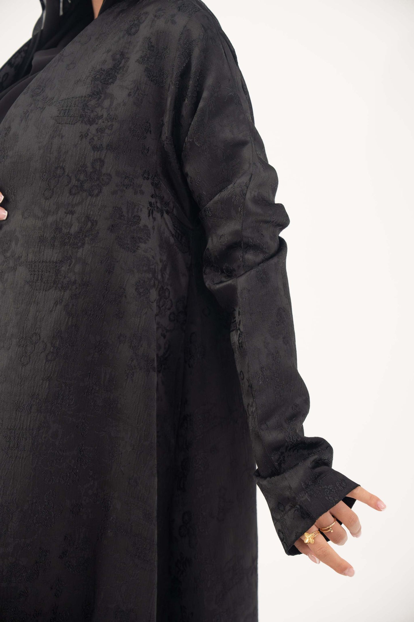 Black jacquard silk abaya with tone-on-tone floral weave, A-line cut, relaxed shoulders, open front, straight sleeves, and discreet side pockets.