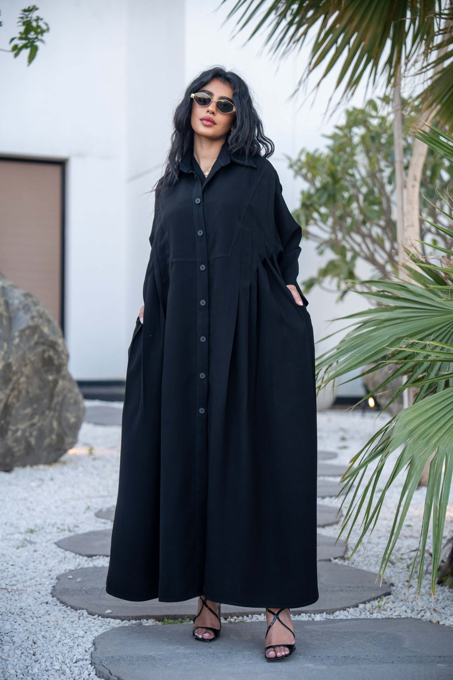 Woman wearing a classic black crepe abaya with a flowing silhouette and button-down front outdoors