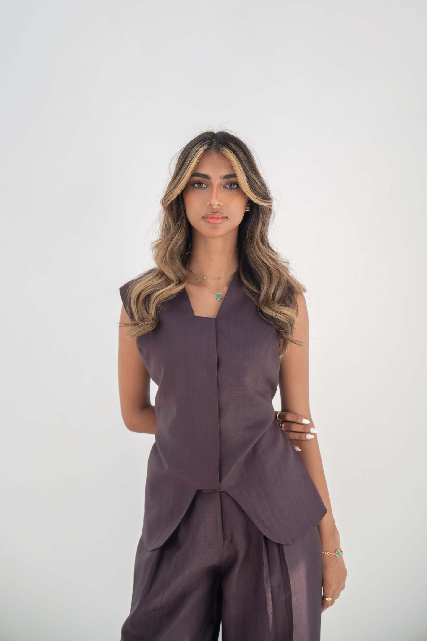 Woman wearing sleeveless ube vest made of high-quality twill linen blend with structured cut and hidden front buttons