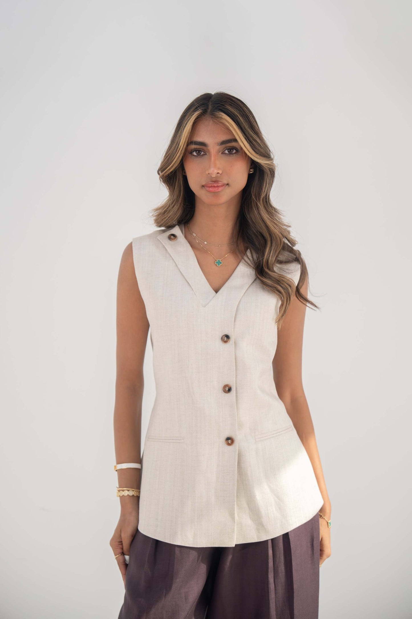 Beige sleeveless twill linen blend vest with V-neck, front buttons, side slits, and removable collar flap.