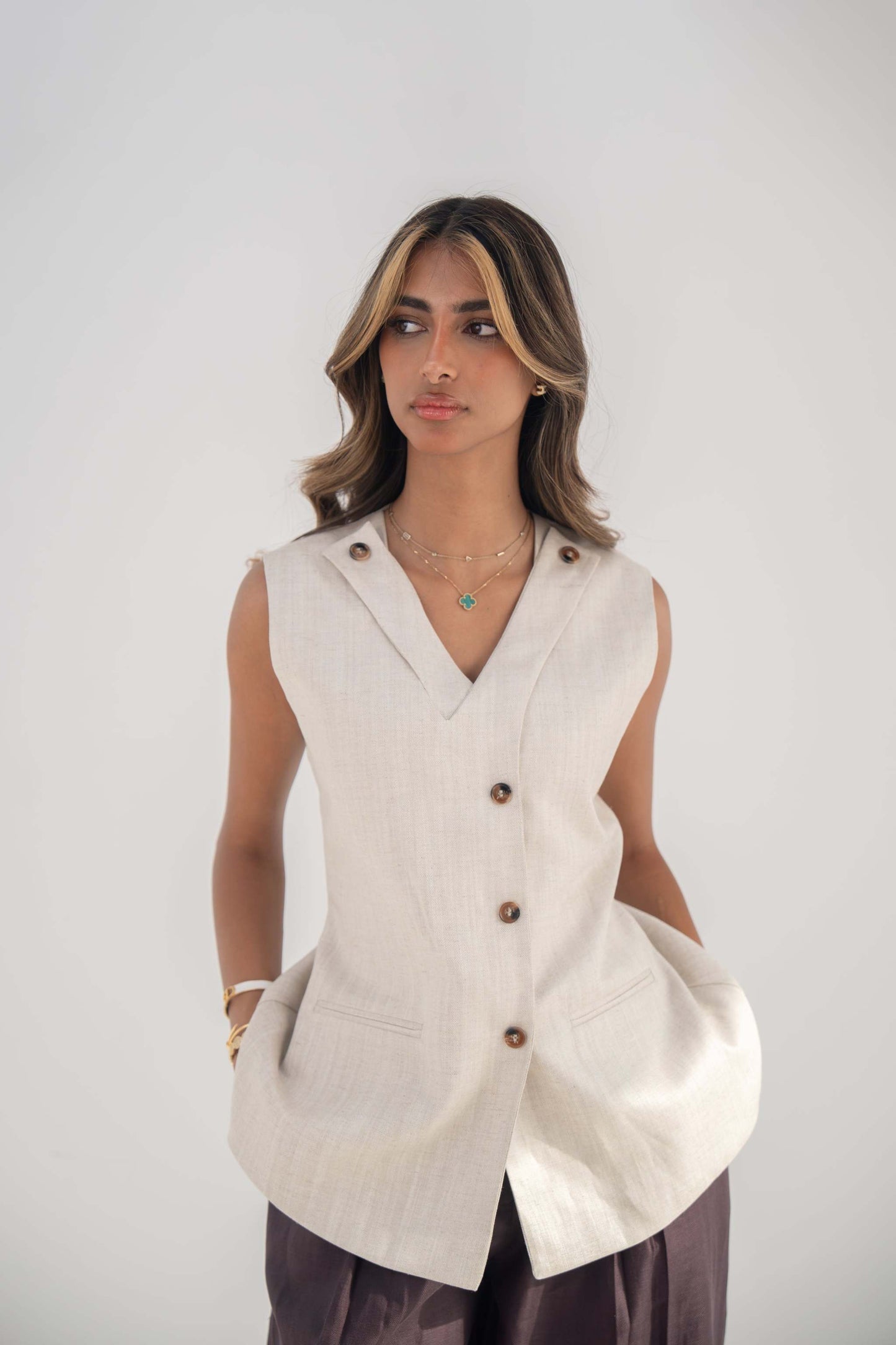 Beige sleeveless Madeleine Vest in twill linen blend with V-neckline, front buttons, curved hem, and removable collar flap.