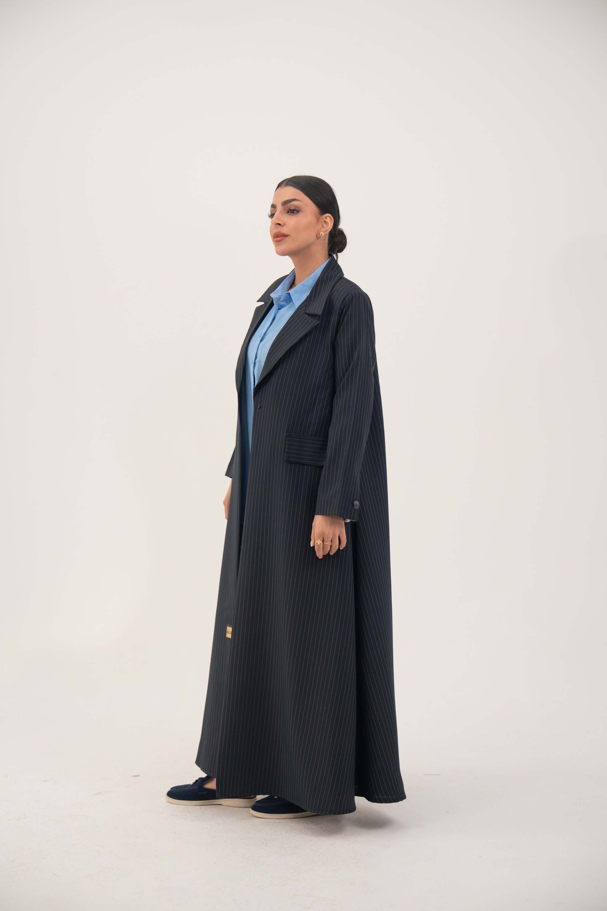 Woman wearing Zanira premium crepe blend open-front navy blazer abaya with white pinstripes and shoulder pads.