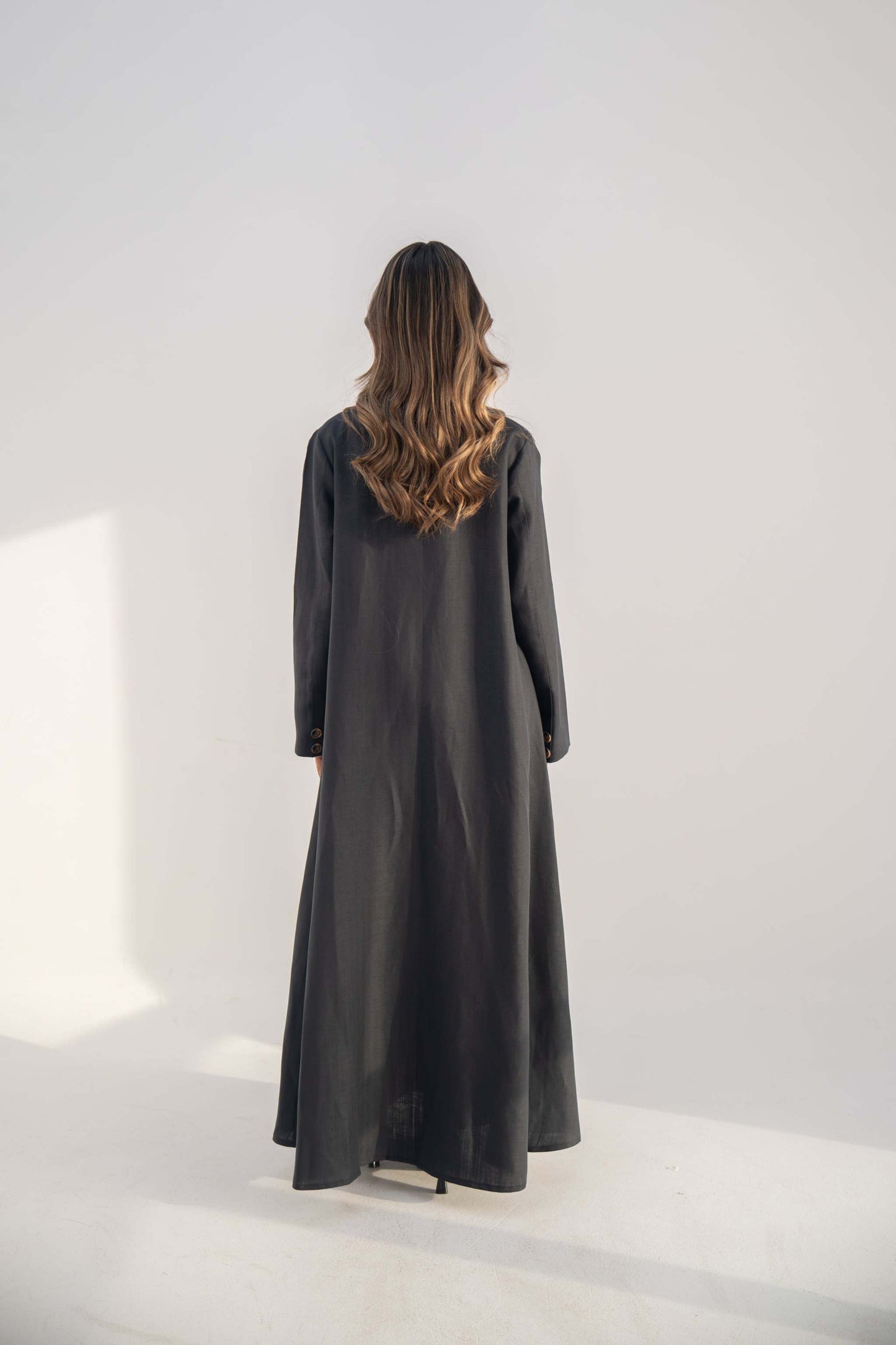 Navy blue blazer abaya in twill linen blend with long clean cut and button details shown from back.