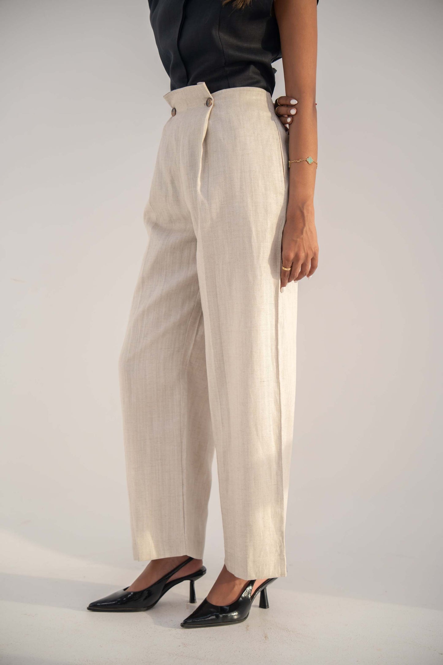 Beige high-waisted Madeleine Pants in twill linen blend with relaxed straight-leg fit, styled with black top and heels.