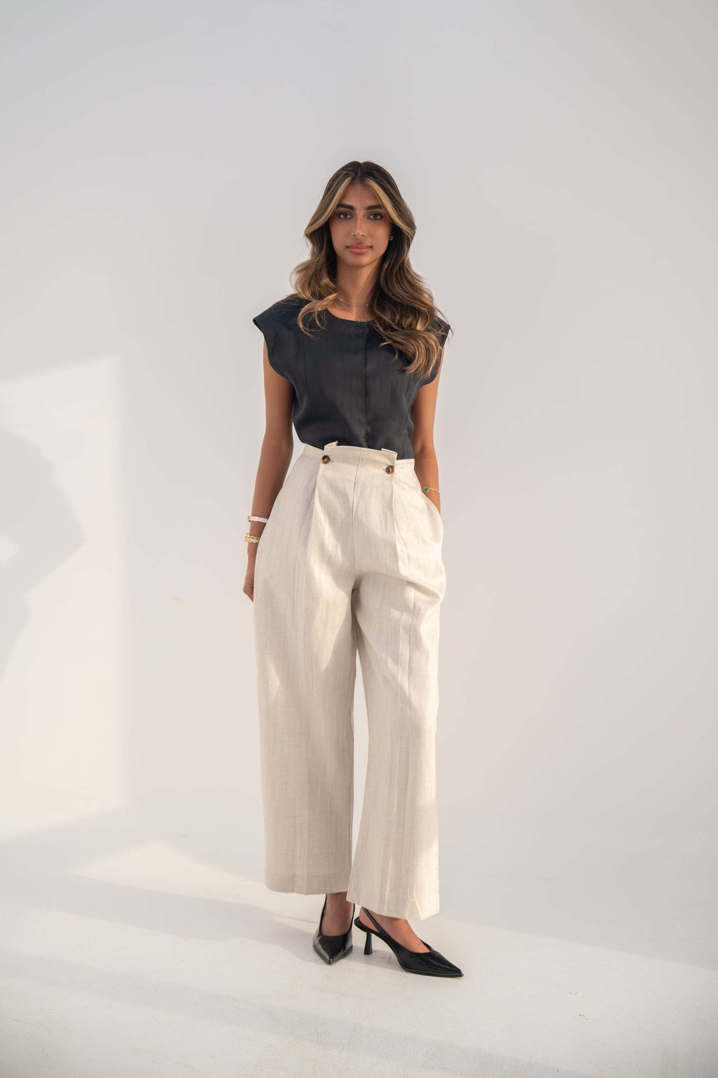Woman wearing beige high-waisted Madeleine Pant with a relaxed straight-leg fit and black top