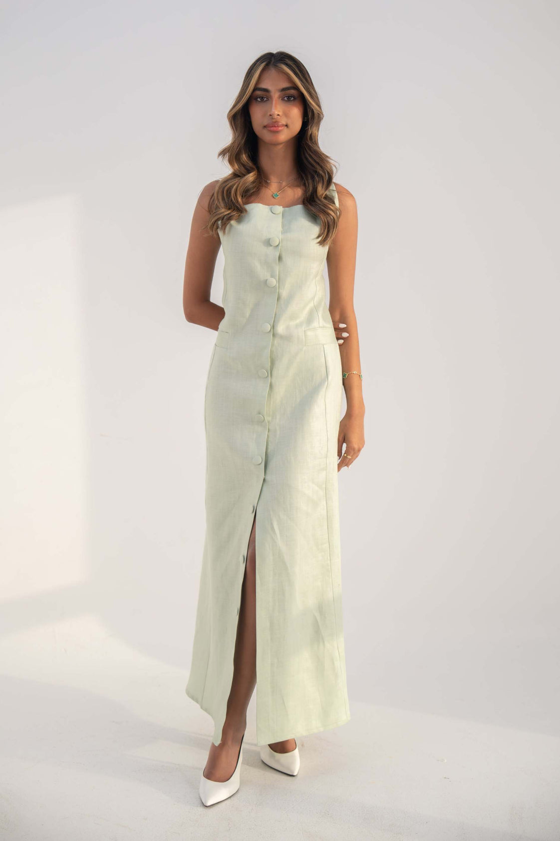 Woman wearing a sleeveless mint green Peppermint Inner dress with front buttons and a front slit