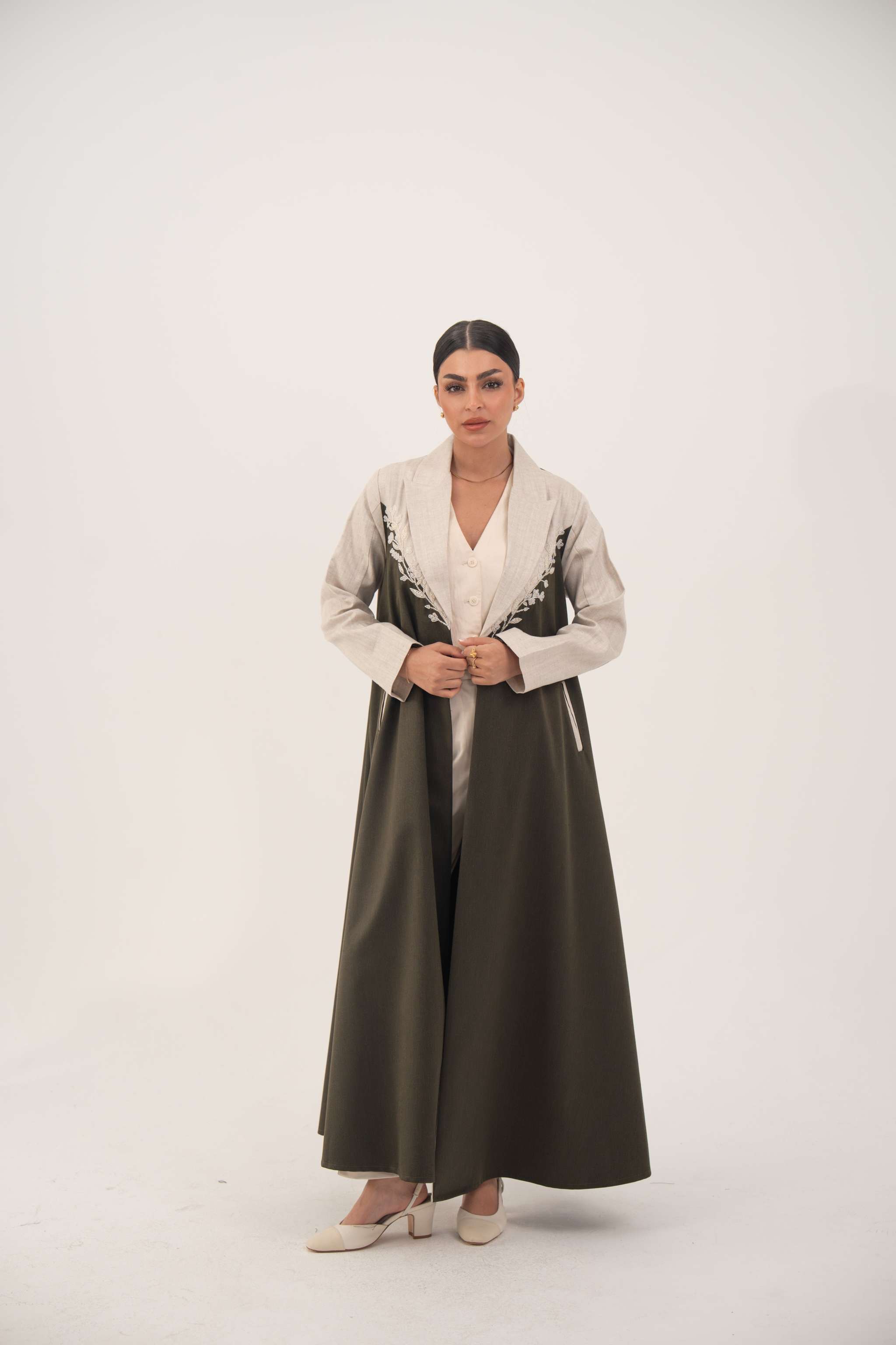 woman wearing olive green abaya crafted from soft twill with beige linen panels and white leaf embroidery