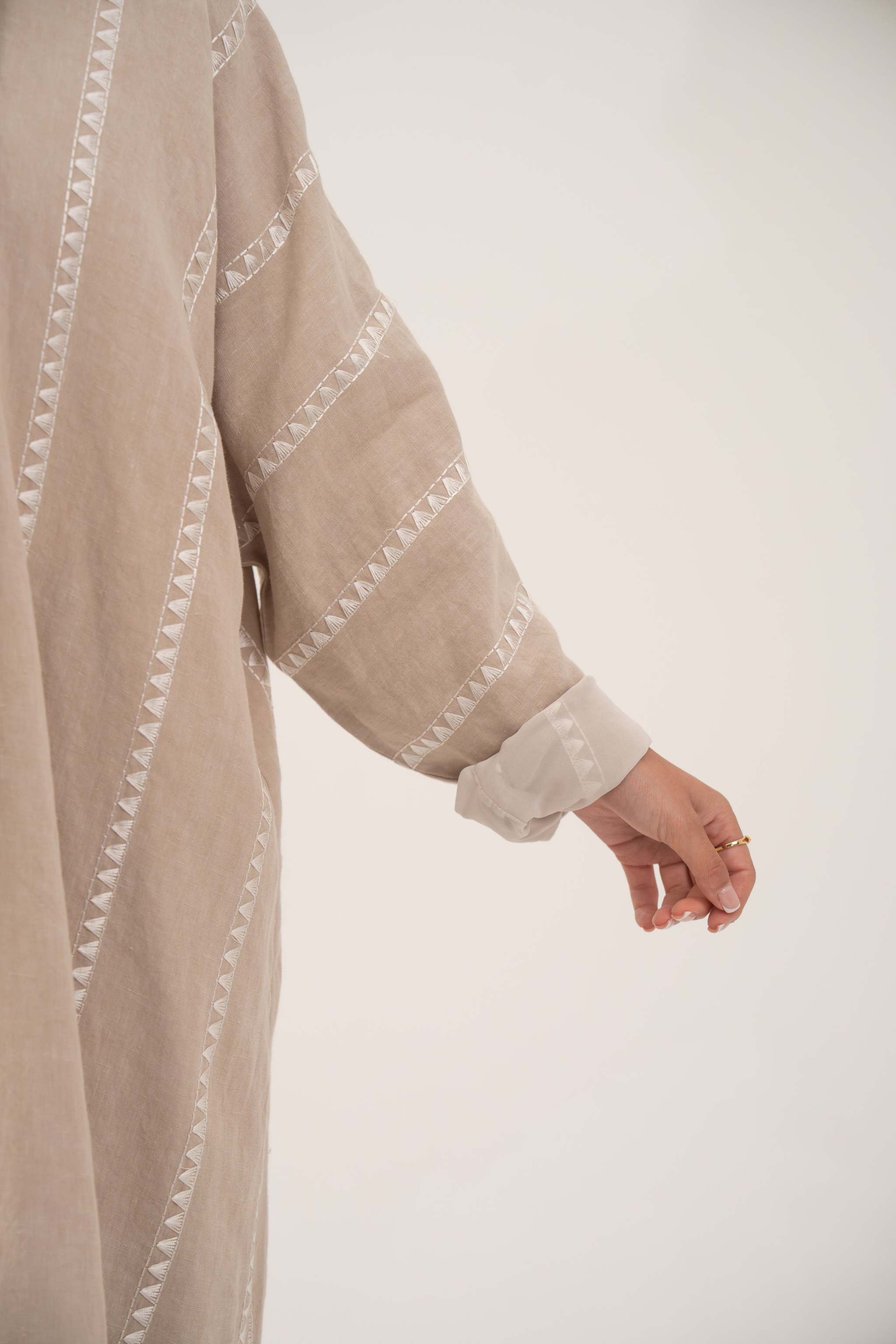 Close-up of beige linen abaya sleeve with subtle tonal embroidery and soft chiffon cuff detail