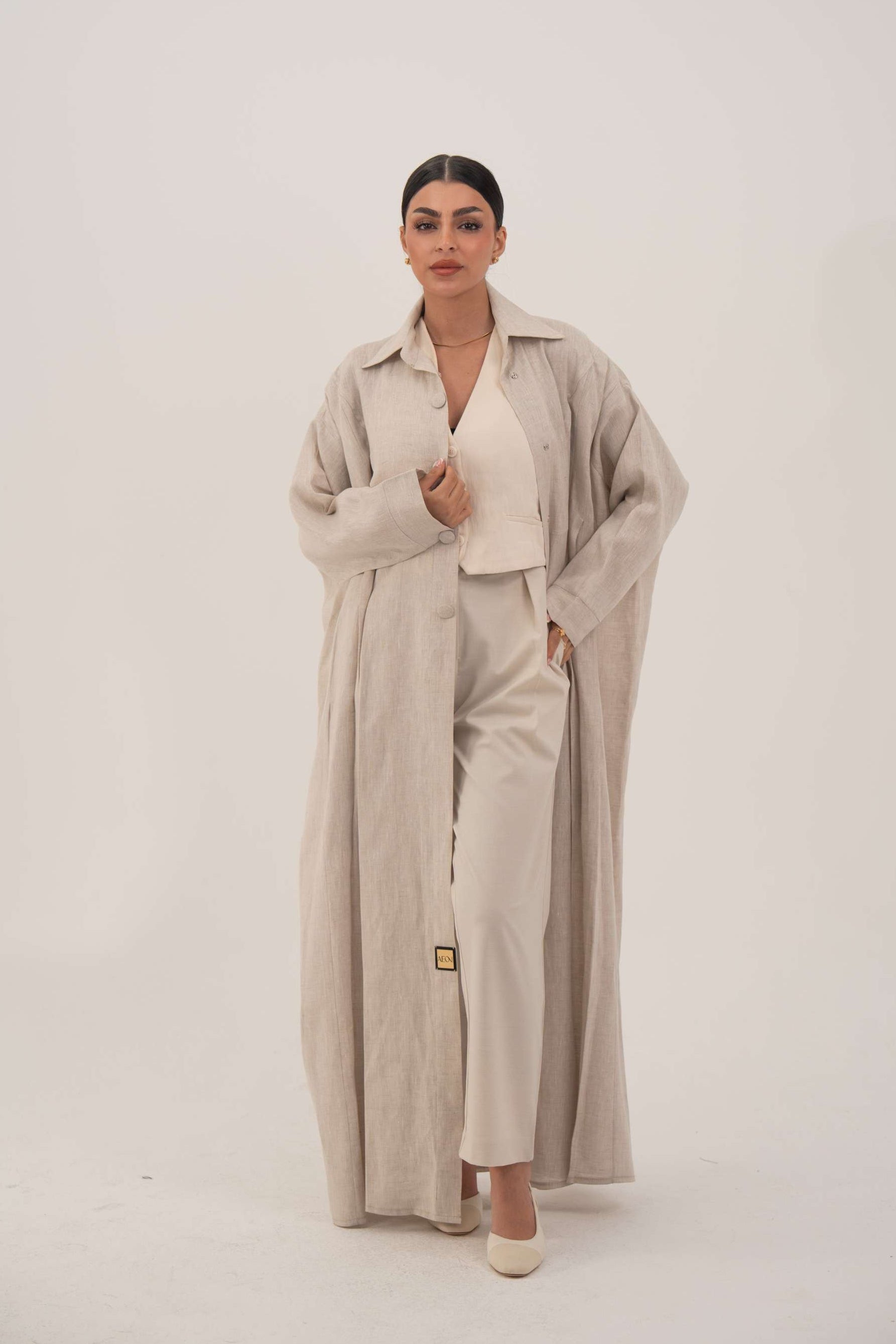 Sandora soft beige linen abaya with classic shirt collar and fabric-covered buttons.