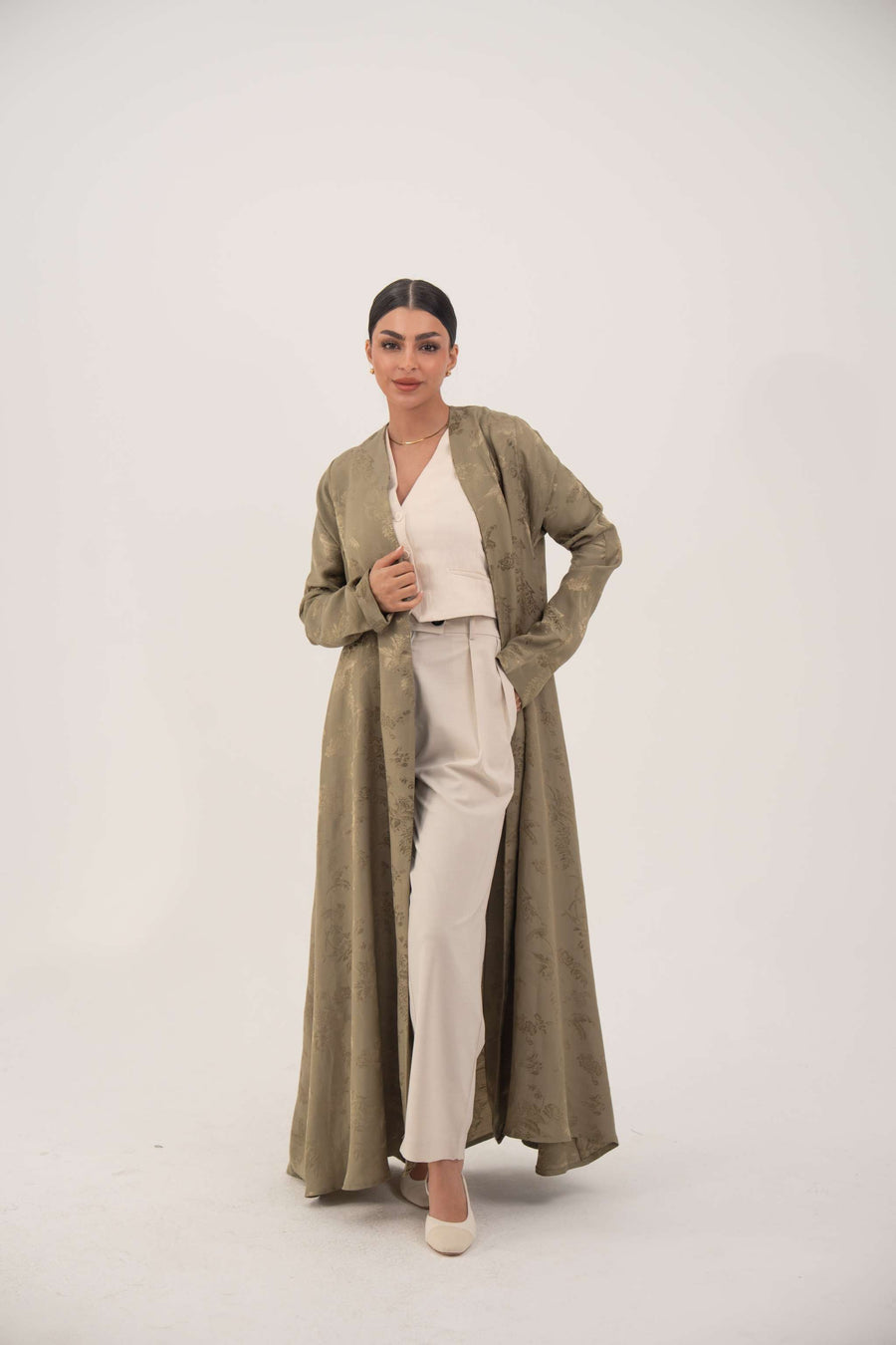 Woman wearing an elegant soft olive green silk abaya with collarless open front and ruched full-length sleeves.