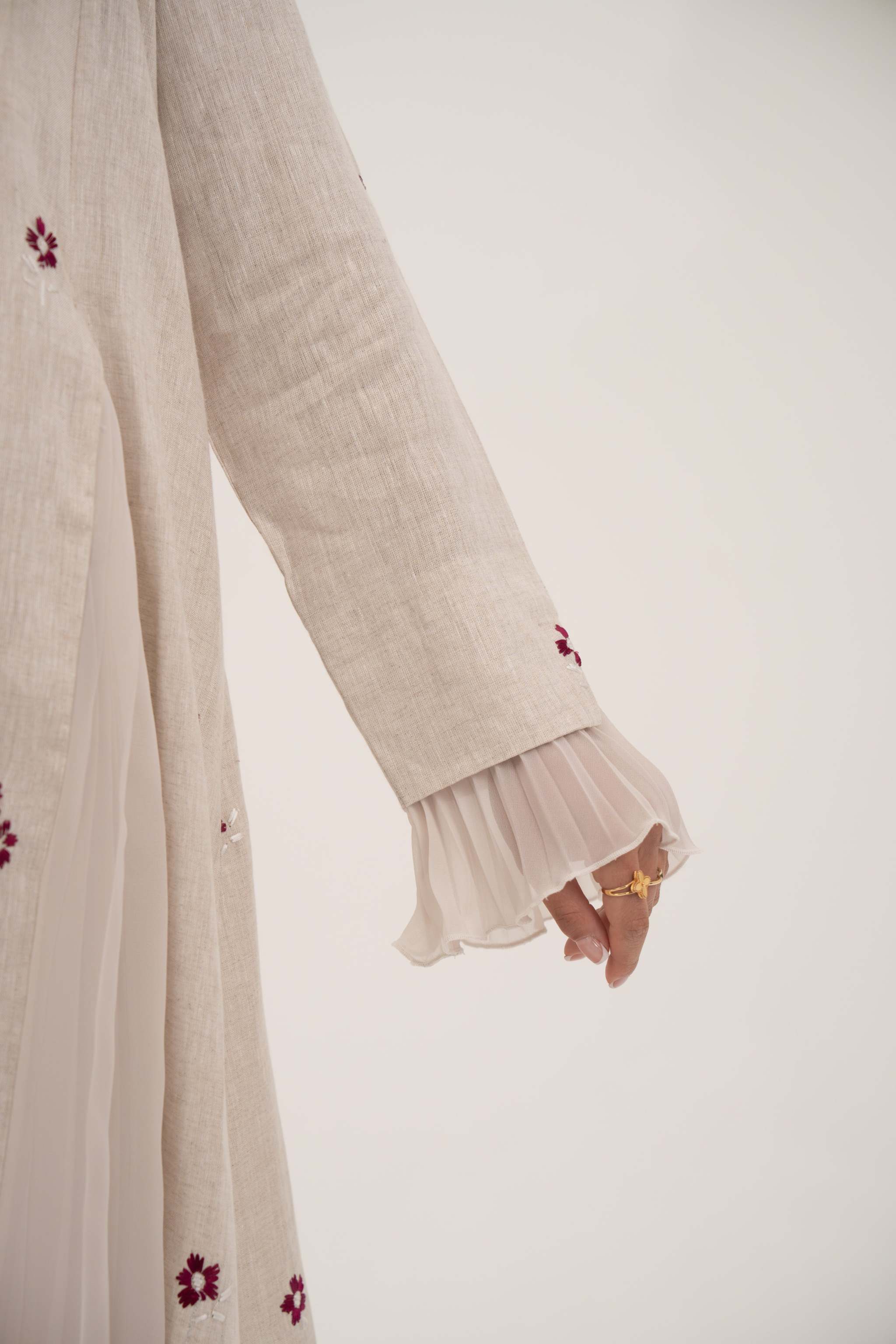 Beige linen abaya with burgundy floral embroidery and soft chiffon pleats on sleeves.