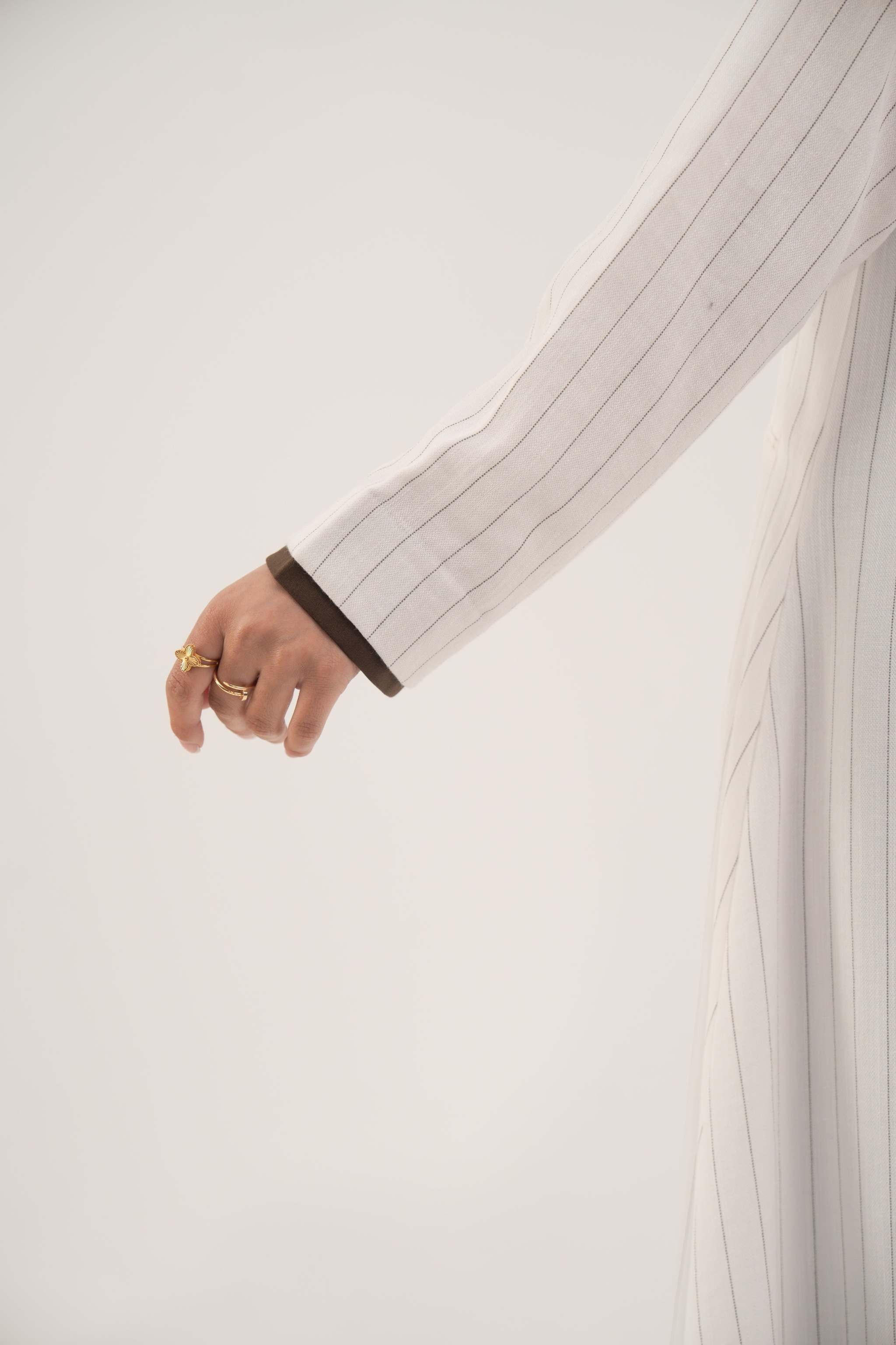 Close-up of a white linen abaya sleeve with grey pinstripes and dark brown inner cuff detailing - Elegant abaya