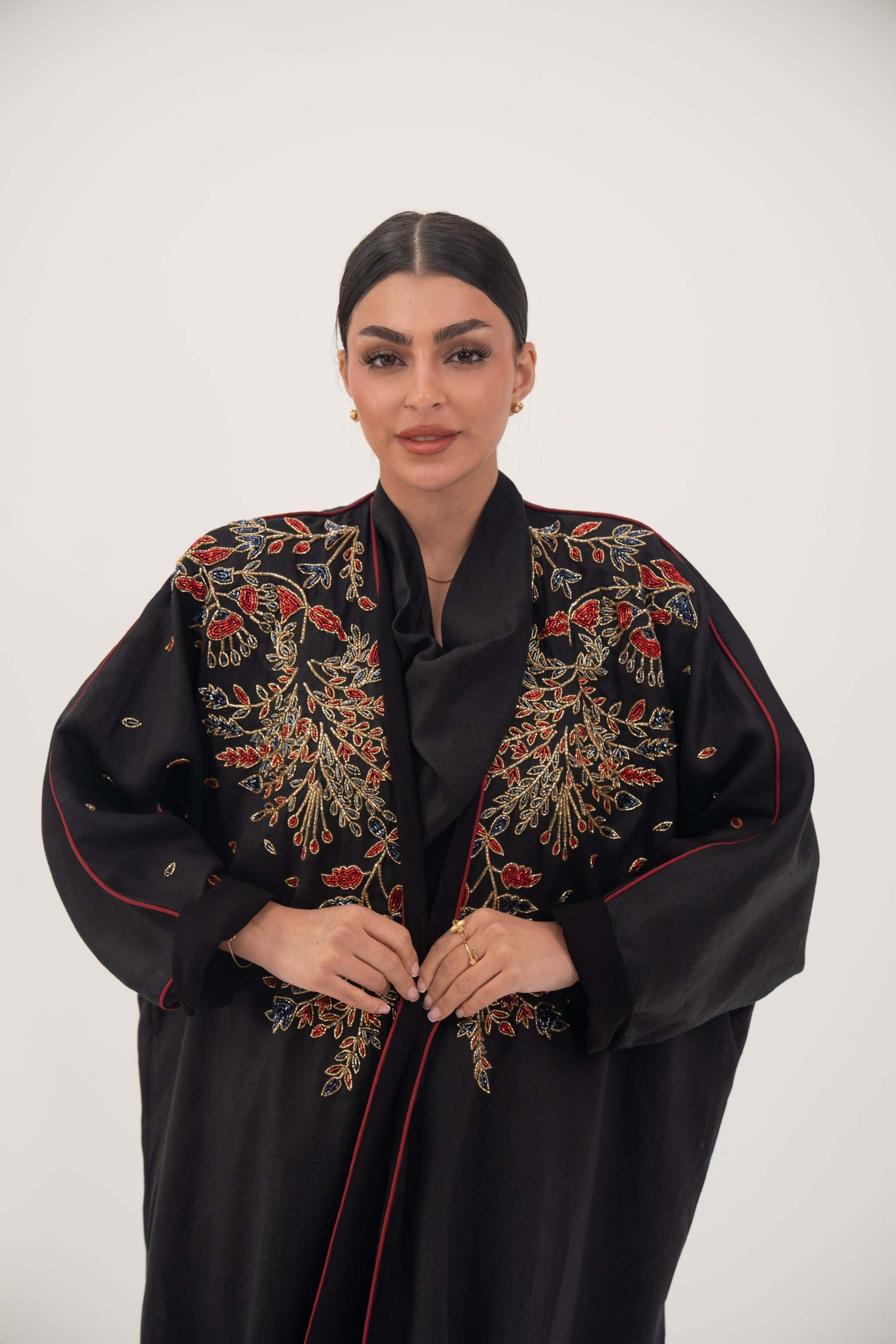 Elegant black linen abaya with multicolored red, gold, and navy shak embroidery and bold red trim