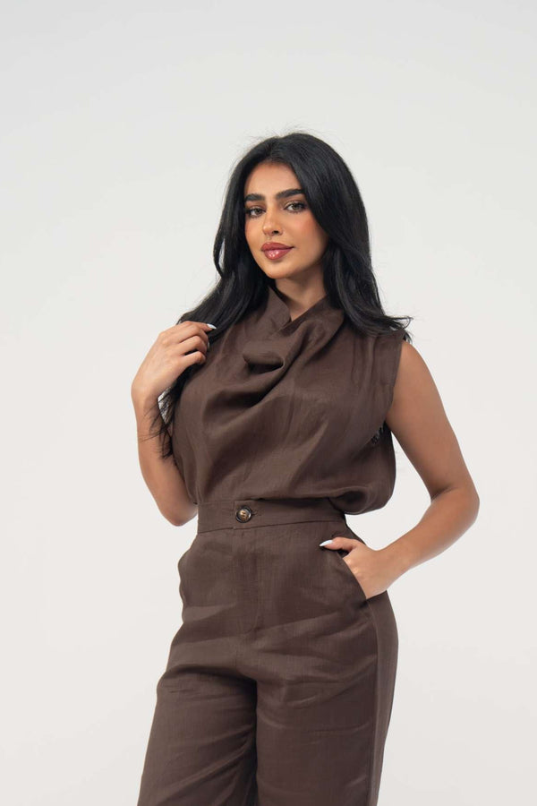 Woman wearing sleeveless warm brown espresso linen blouse with soft draped neckline and light pleats paired with matching pants