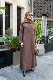 Woman wearing classic brown crepe abaya with hijab and sunglasses outdoors