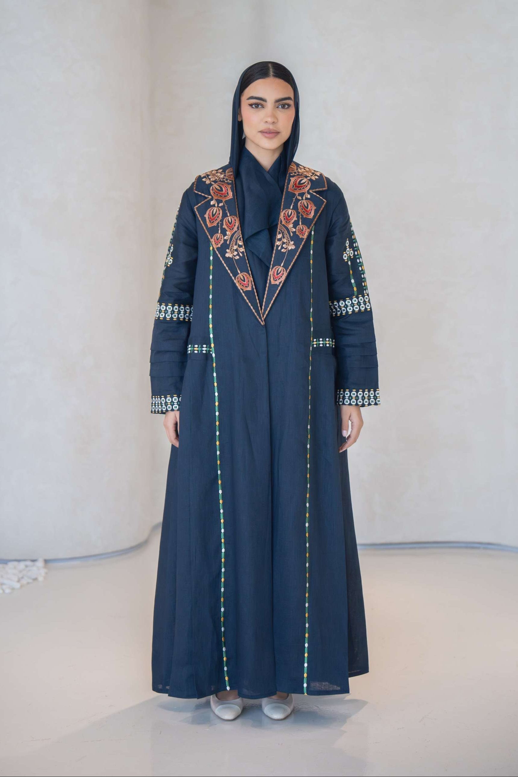 Navy blue breathable lightweight linen abaya with colorful floral hand-embroidery and structured notched lapel collar.