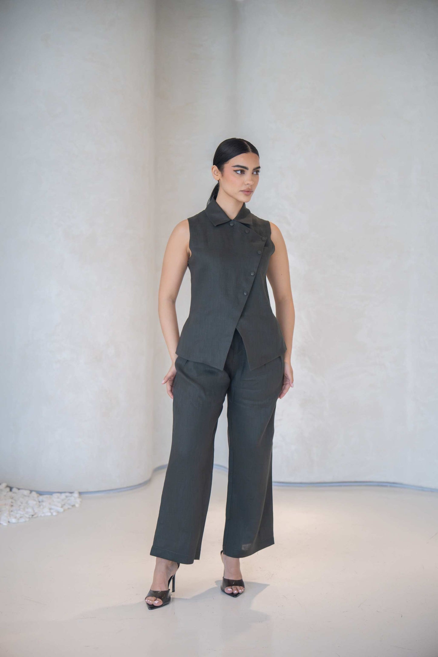 Woman wearing dark gray high-waisted wide-leg Gray Pant with sleeveless matching top and black heels in minimalist setting