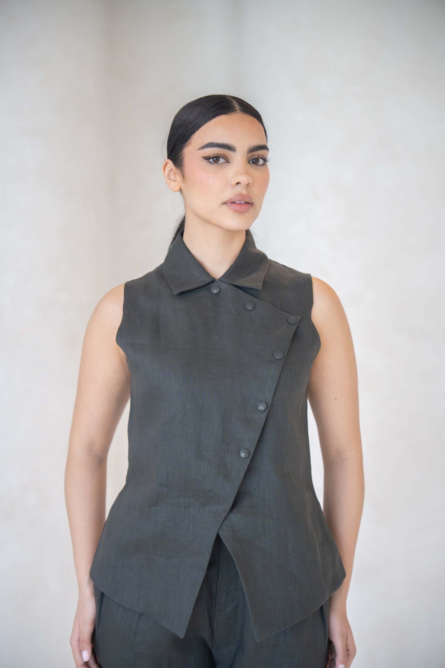 Woman wearing charcoal gray vest with asymmetrical buttoned front and shirt collar.