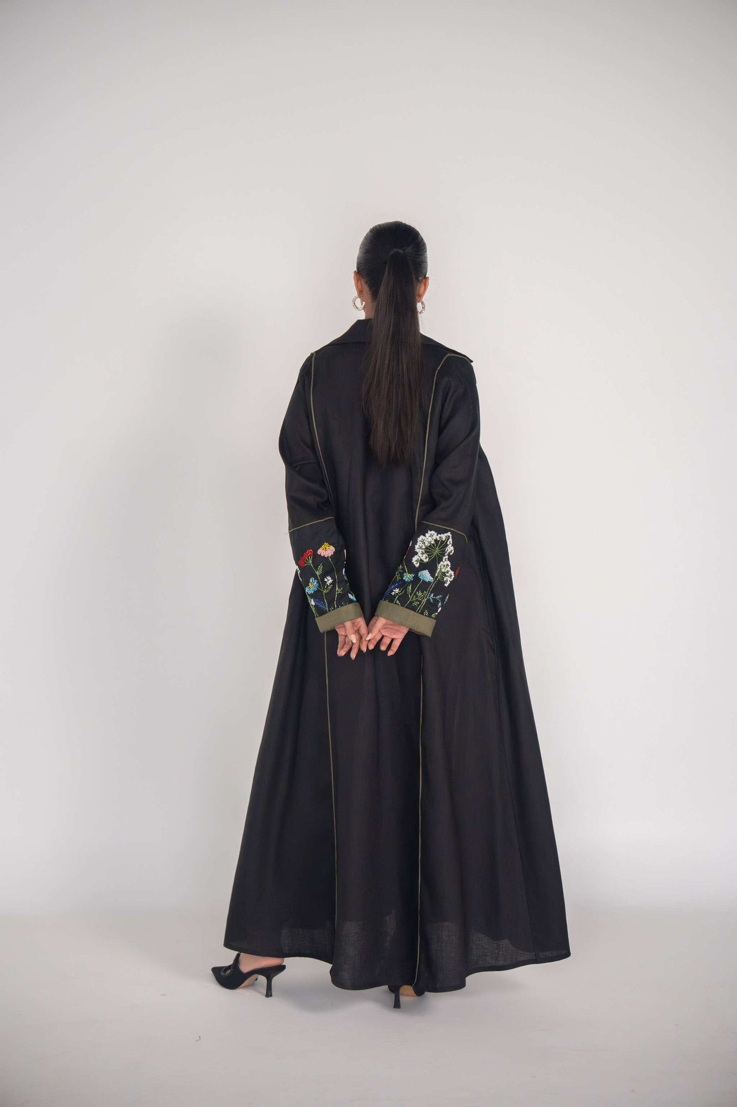 back view of black abaya with embroidered sleeves and olive green box pleats