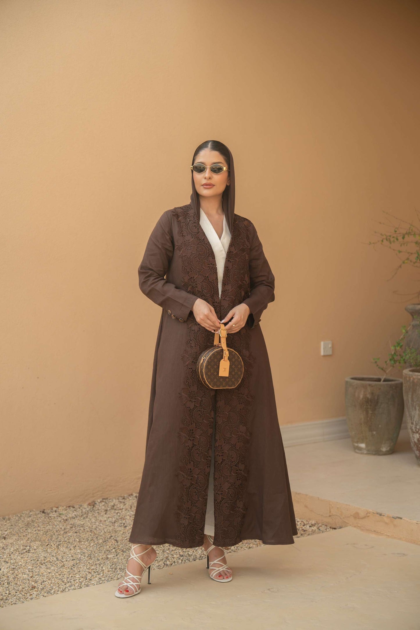 Woman wearing deep mocha brown Mocha Bloom Abaya with floral embroidery and open front style standing outdoors
