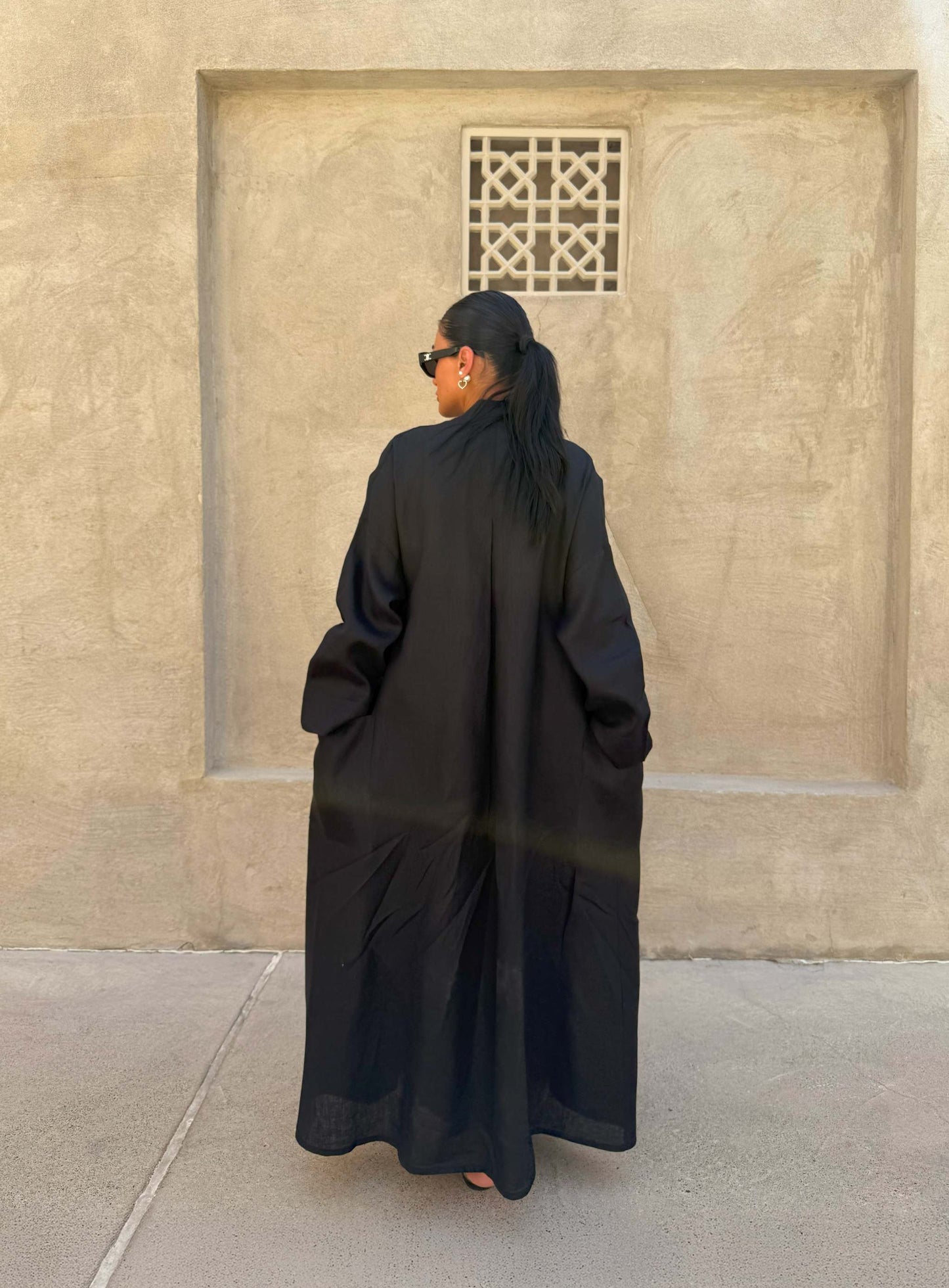 Minimalist black linen abaya with straight cut and open front, featuring subtle stitching and a flowy silhouette.