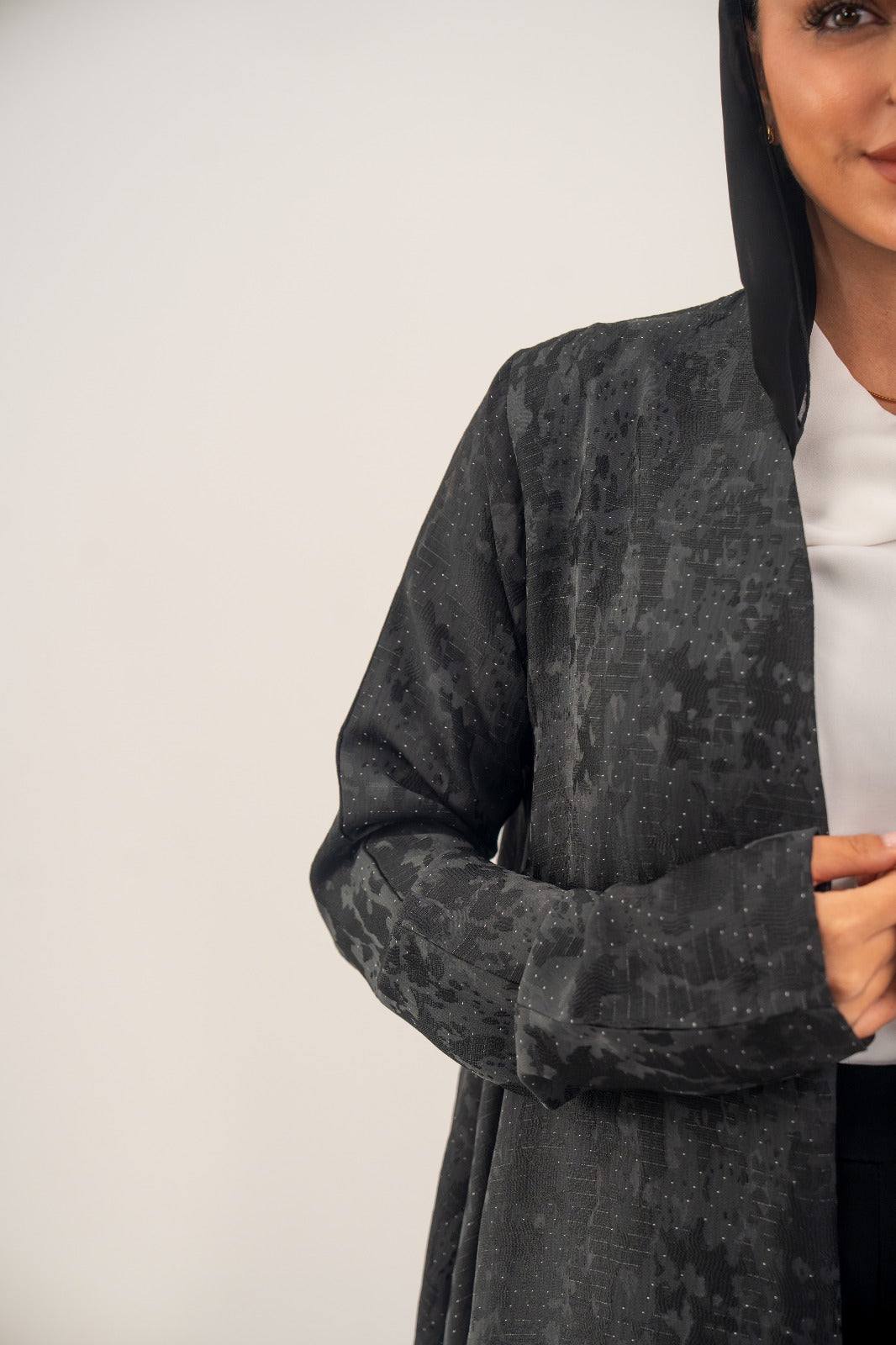 Black silk open-front abaya with subtle glossy finish and delicate abstract woven pattern