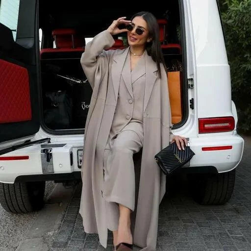 Woman wearing beige drift abaya with relaxed freesize cut and soft crepe fabric sitting by white SUV.