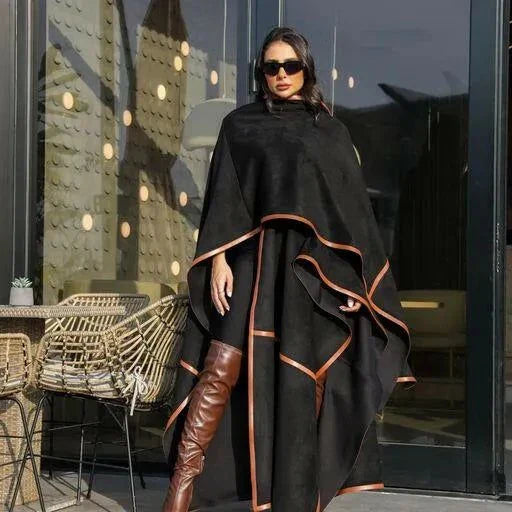 Woman wearing black leather-trimmed chamois poncho with brown knee-high boots and sunglasses outdoors - Leather Trace