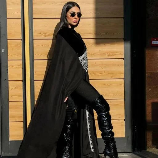 Woman wearing Midnight Veil black chamois and velvet cape with thigh-high boots and sunglasses standing against wooden wall