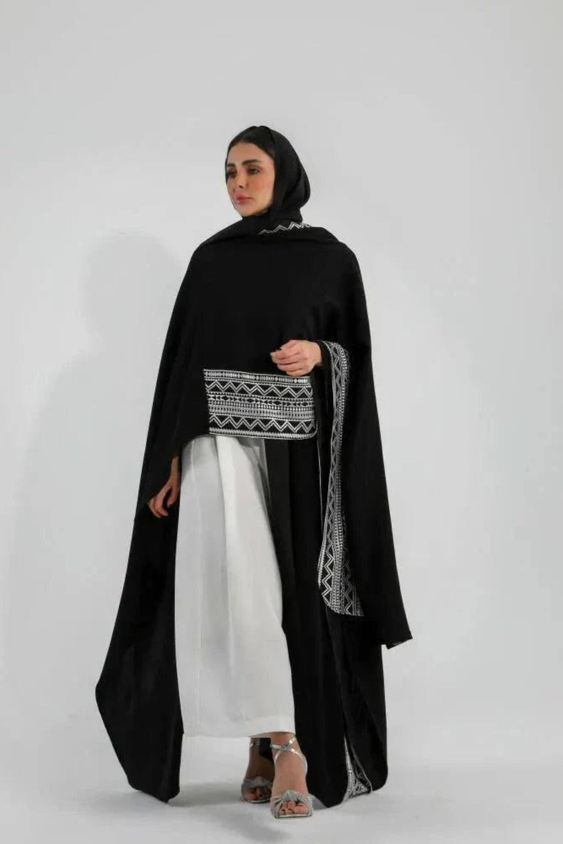 Woman wearing black crepe bisht with white Sadoo hand embroidery and open front design over white outfit