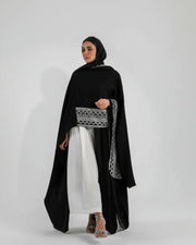 Woman wearing black crepe bisht with white Sadoo hand embroidery and open front design over white outfit