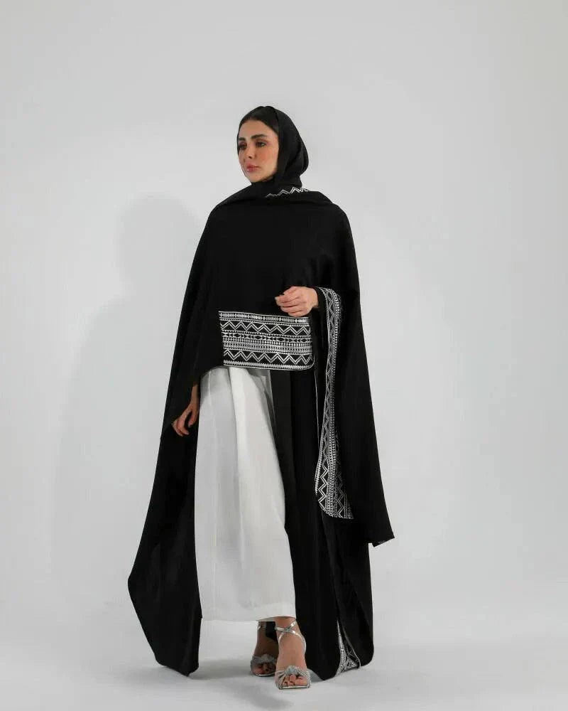 Woman wearing black crepe bisht with white Sadoo hand embroidery and open front design over white outfit