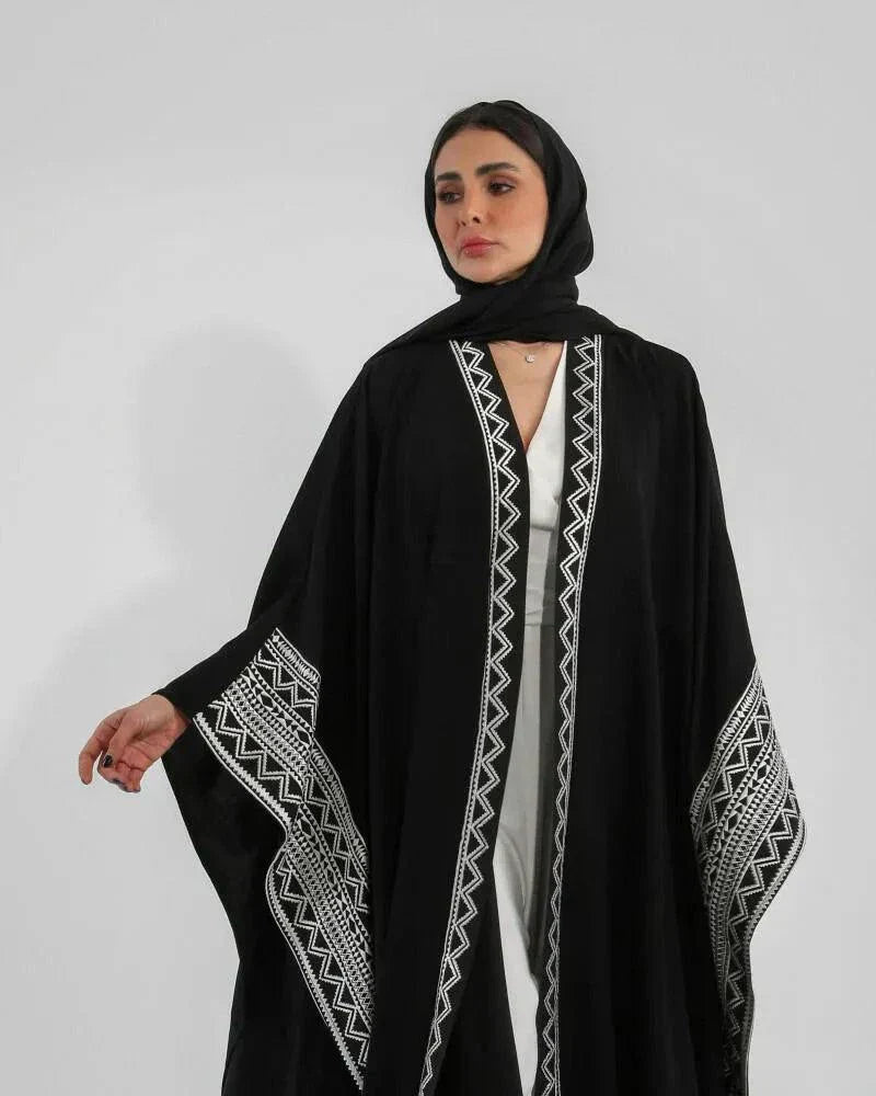 Woman wearing black crepe bisht with white Sadoo hand embroidery and open front design over white outfit