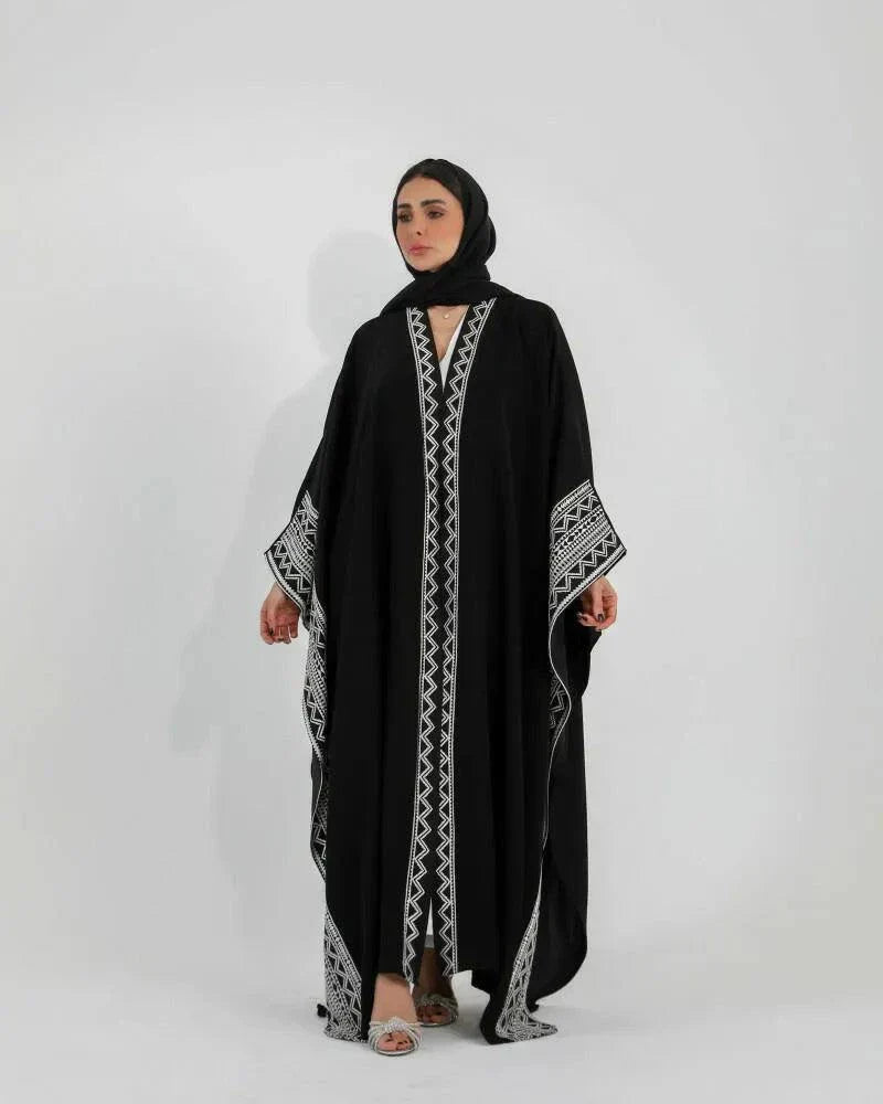 Woman wearing black crepe bisht with white Sadoo hand embroidery and open front design over white outfit
