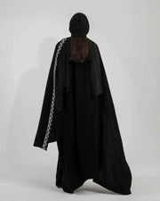 Woman wearing black crepe bisht with white Sadoo hand embroidery and open front design over white outfit