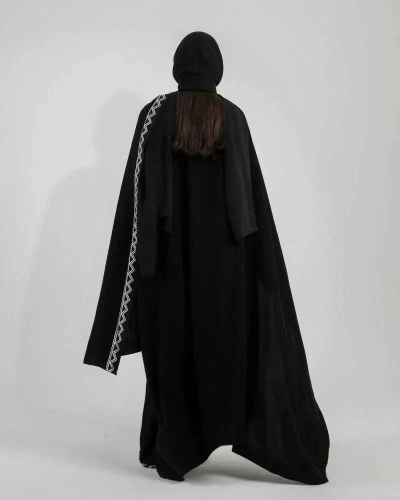 Woman wearing black crepe bisht with white Sadoo hand embroidery and open front design over white outfit