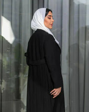 Black blazer-style abaya in crepe fabric with tailored front and soft pleats at the back, featuring sharp lapels and a clean silhouette.