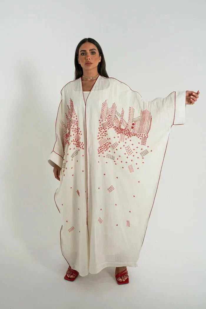 White linen bisht abaya with red hand embroidery and red trim, styled with a red handbag and sandals - Strawberry Cheesecake