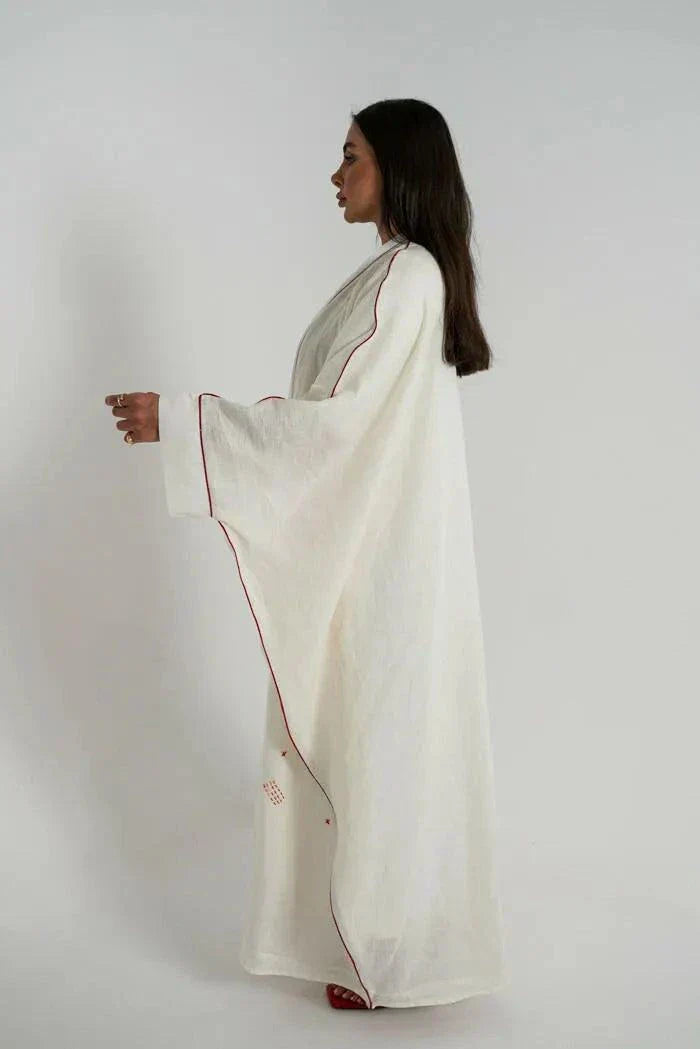 White linen bisht abaya with red hand embroidery and red trim, styled with a red handbag and sandals - Strawberry Cheesecake