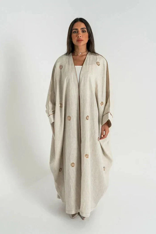 woman wearing beige linen bisht abaya with delicate hand embroidery and relaxed fit