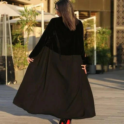 Woman wearing a chic black Velvet Noir blazer-style abaya with velvet panels and flowing crepe fabric outdoors.
